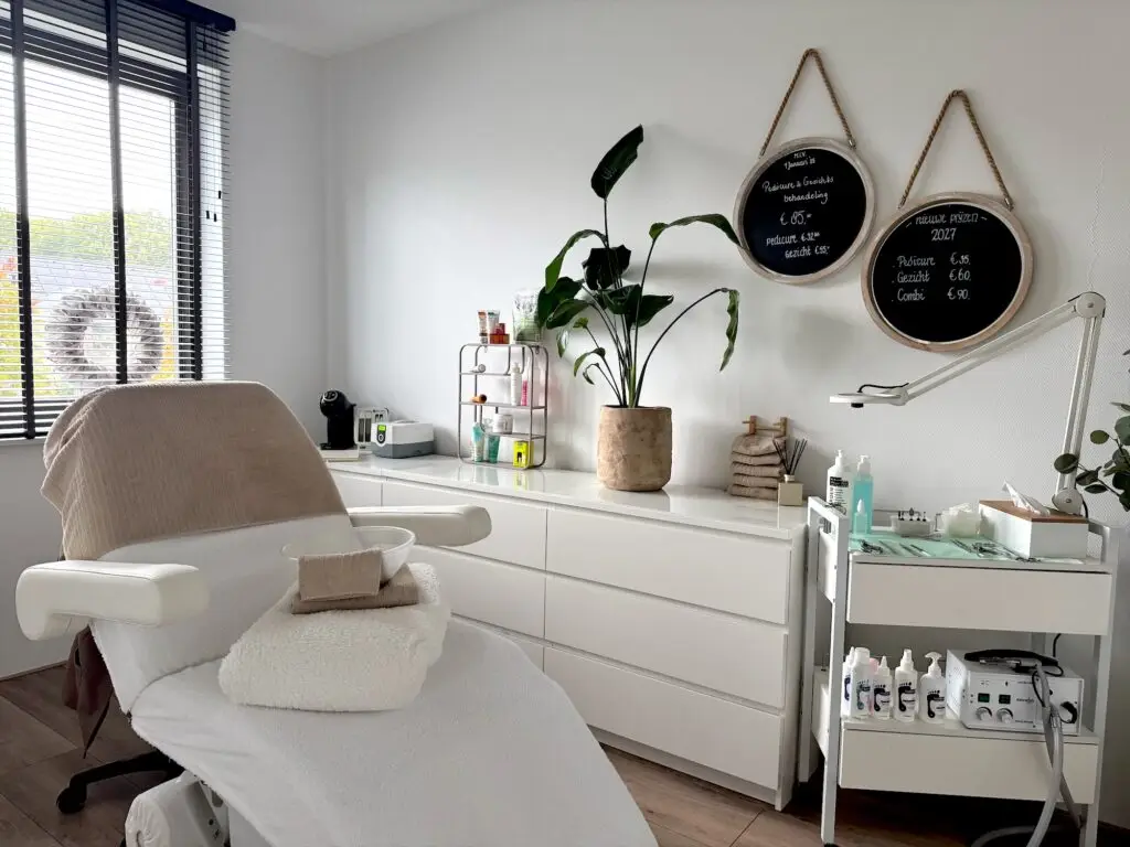 Overzicht van de salon: behandelstoel, een grote plant, een witte kast en twee ronde bordjes aan de muur.